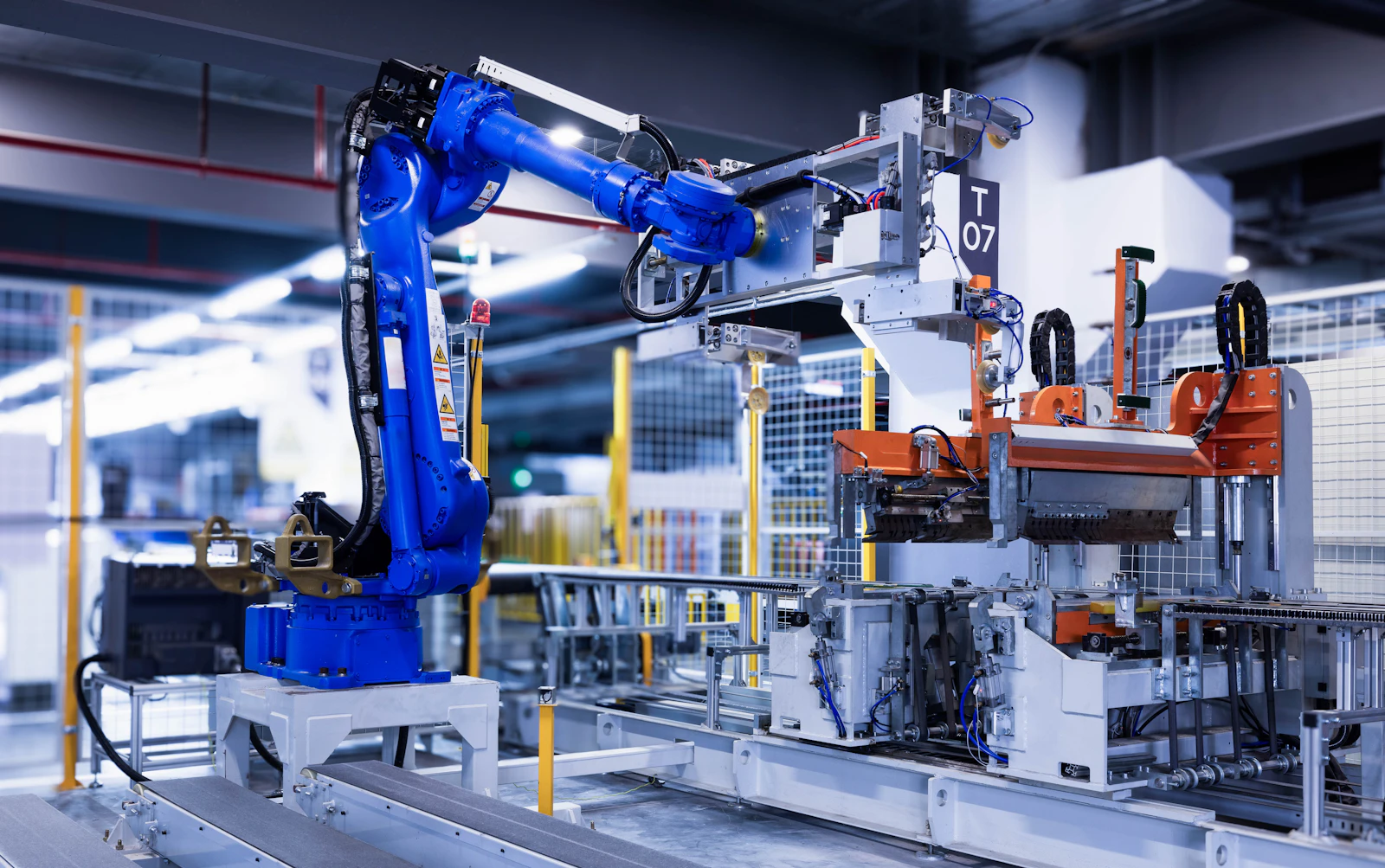 A blue industrial robot arm beside a production fixture.